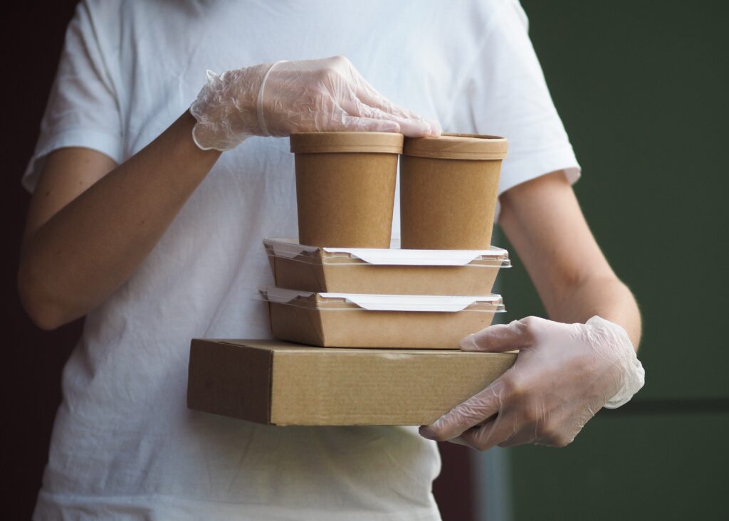 Environmentally friendly food packaging held by a food takeaway employee